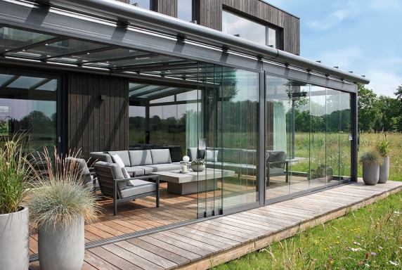 Terrassenüberdachung mit Glasdach und seitlichen Glaselementen für geschützten Außenbereich